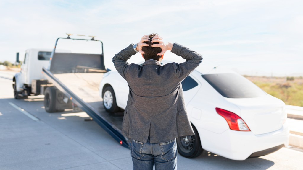 A man looking very upset as his car is towed