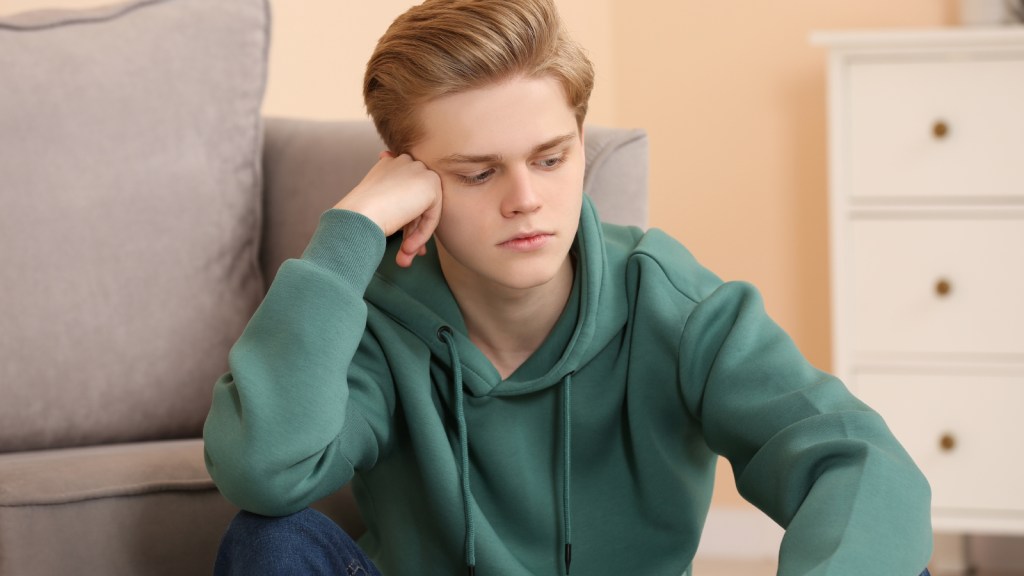 A young man sitting on the floor looking upset