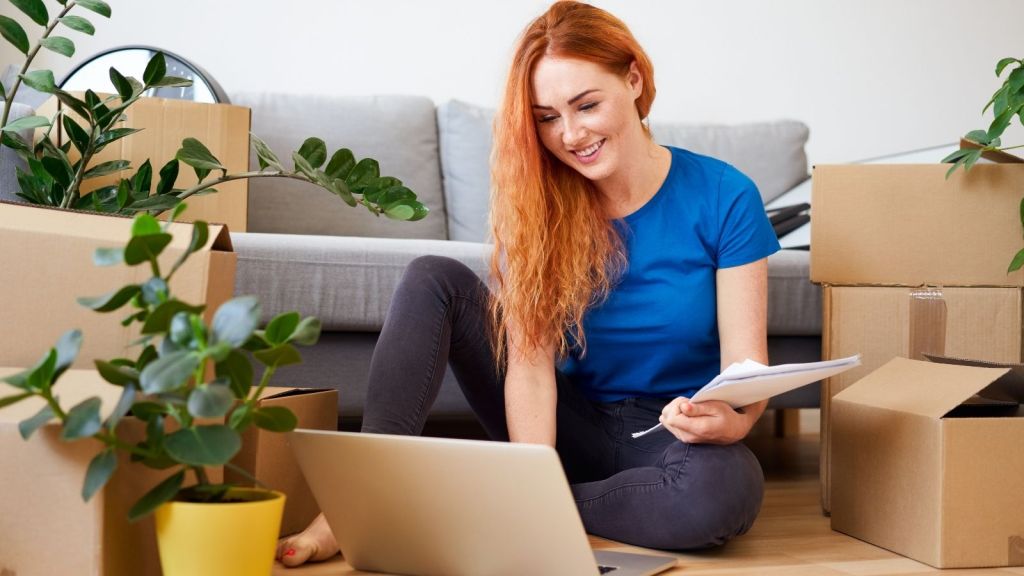 woman on laptop among moving boxes