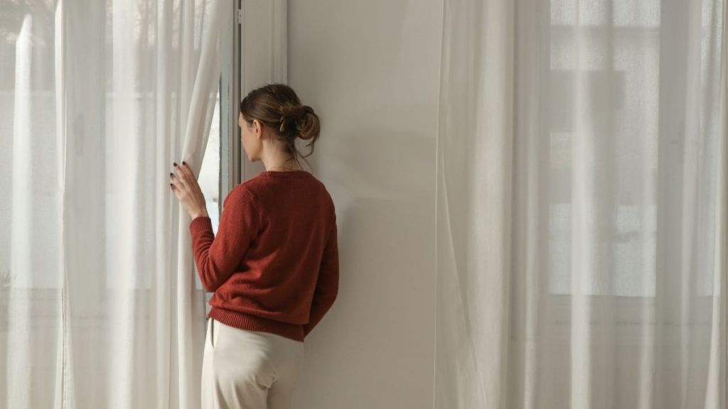 woman peering through curtains