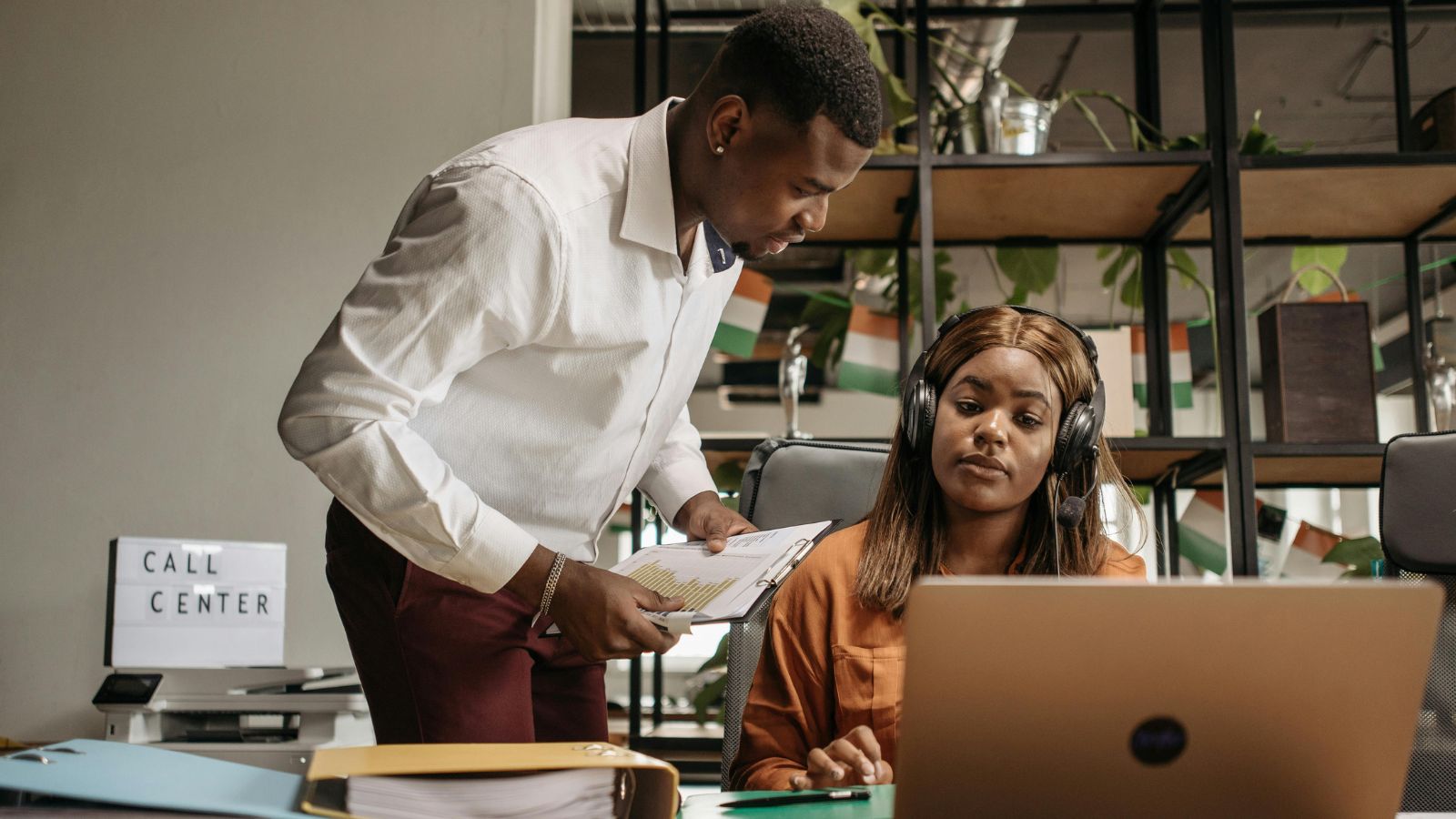 Man leaning into a woman in headphones in an office