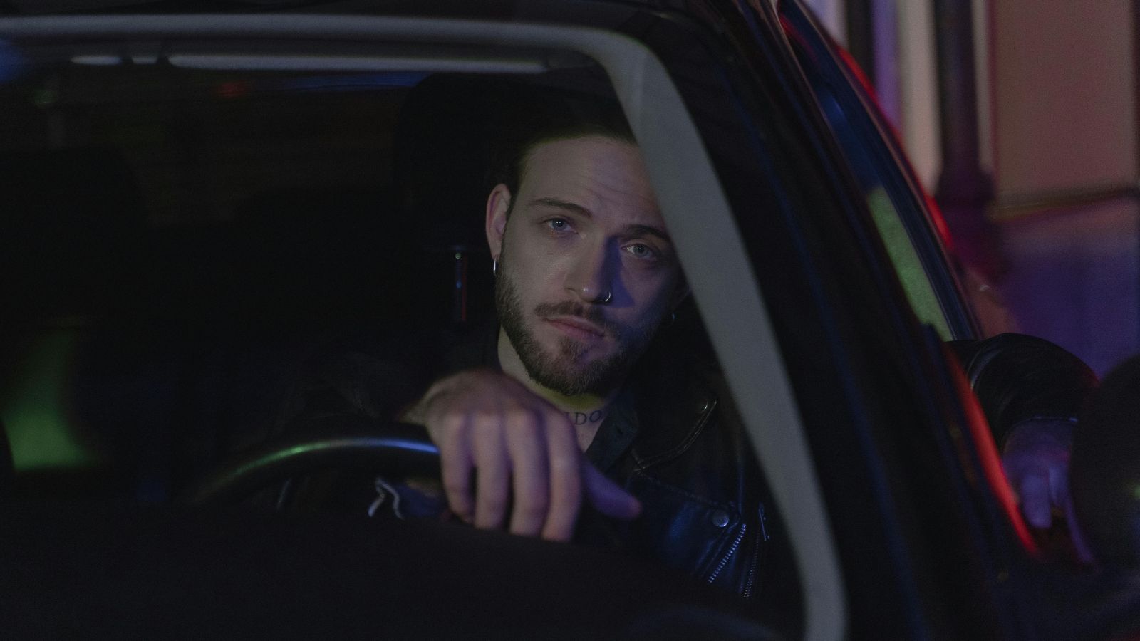 Solemn man driving a car at night