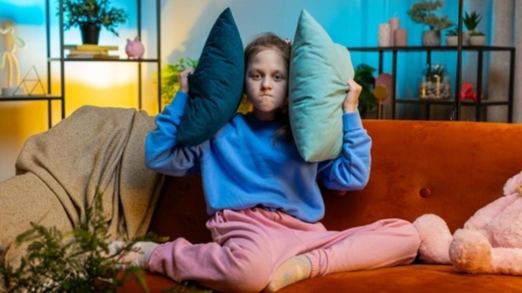 Girl with pillows over ears