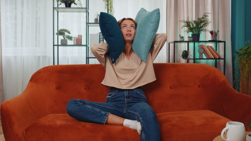 Woman with pillows over ears