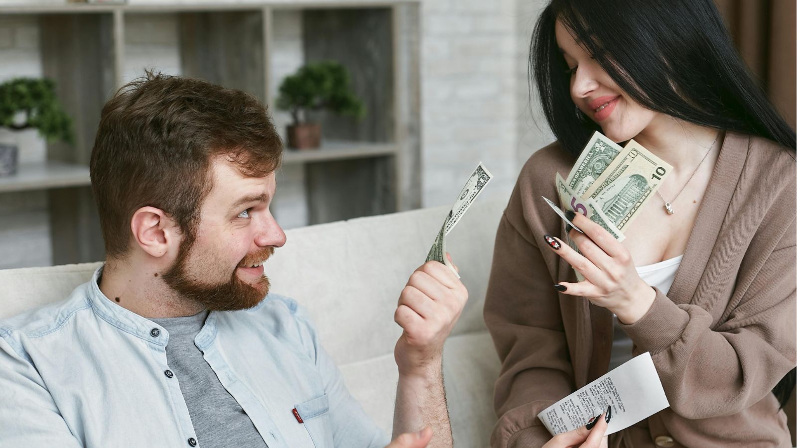 Man and woman discussing money while holding dollar bills and a receipt