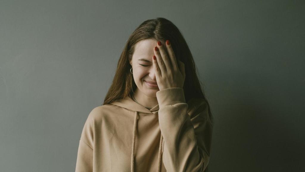 Woman holding her hand over her face after laughing at a customer
