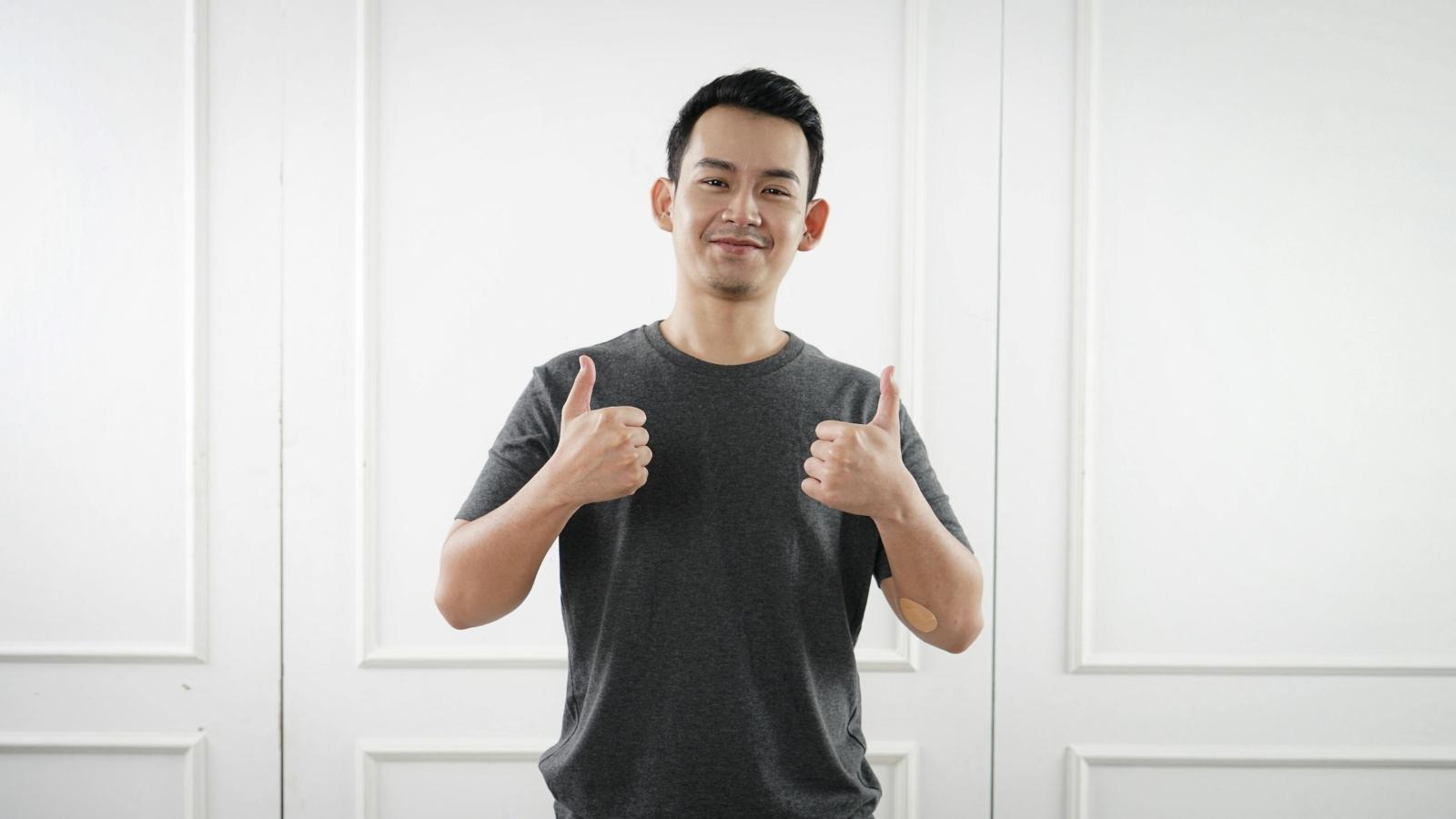 Millennial man standing with his thumbs up