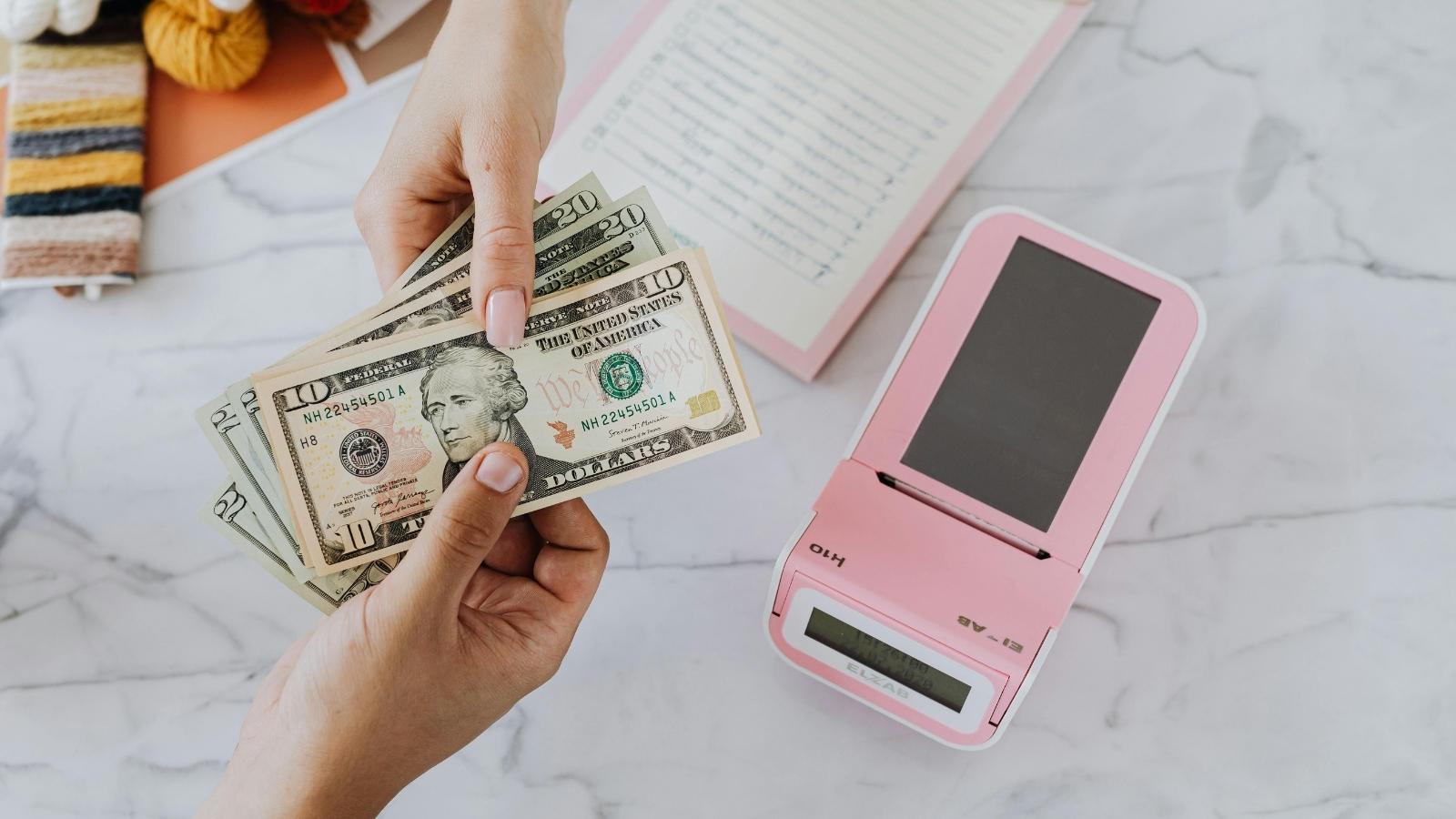 Cashier Fans Herself During Slow Shift, but Customer Makes Strange Claim About Cash Register Money Customer handing cash to a cashier