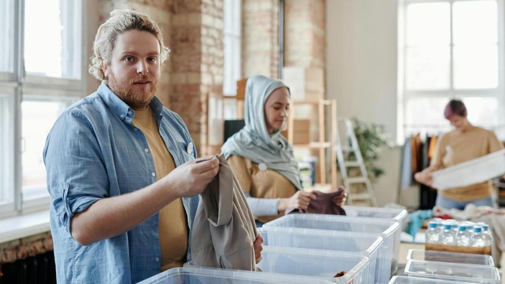 Man folding clothes that he's donating to a charity