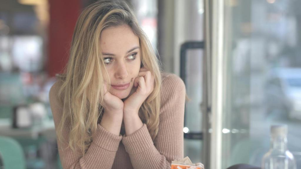 Blonde woman holding her face and thinking about what she did
