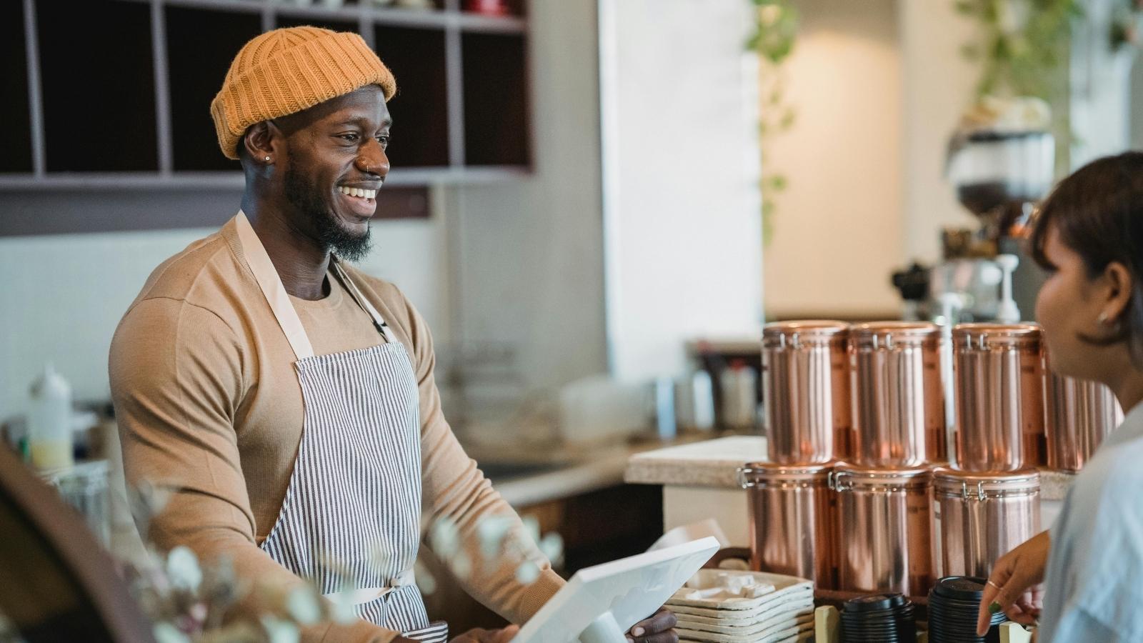 The Espresso Trap: Why a Barista’s Raw, No Nonsense Response to a Toxic Coffee Complaint Left a Cafe Line Completely Stunned Man smiling as he helps a customer order coffee