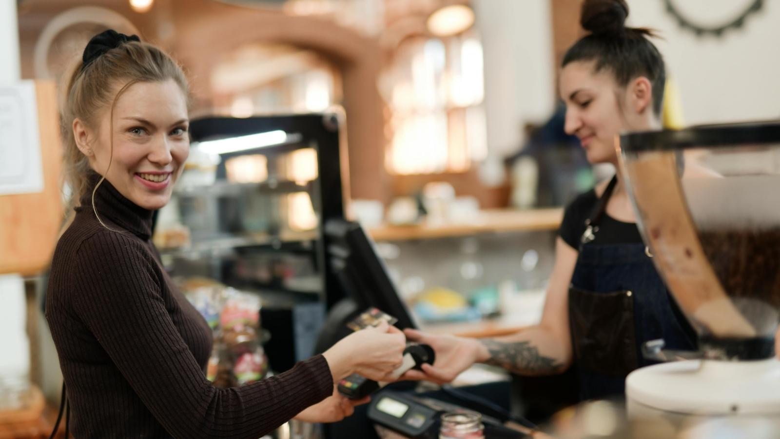 Woman smiling and standing behind a register. 
