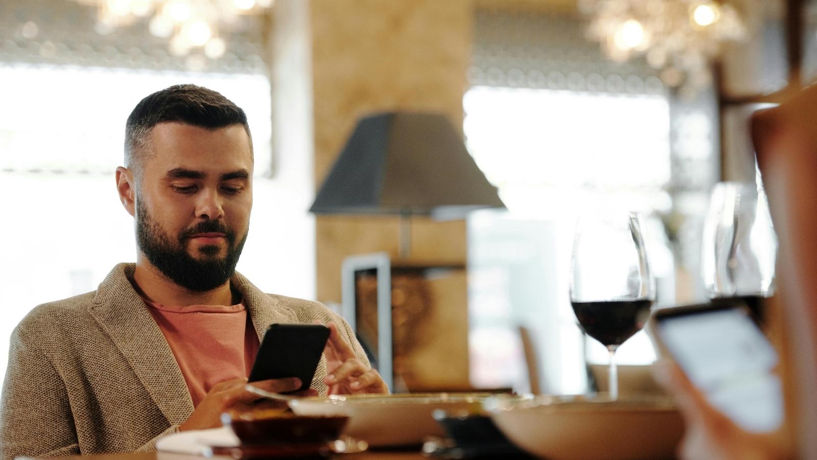 Man sitting at dinner with his wife, texting his in-laws