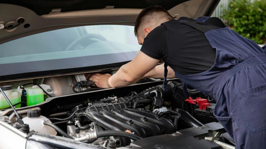 Man working under the hood of an older vehicle