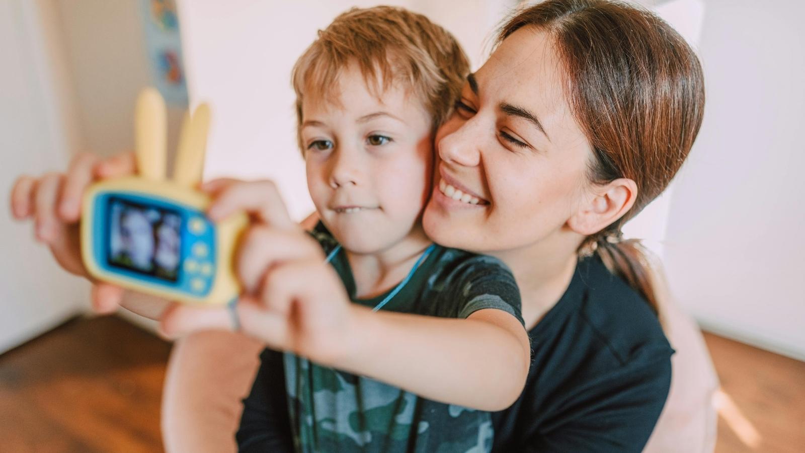 A Honeymoon Childcare Plan Sparked Unexpected Tension Between Grandparents Woman and her six-year-old son playing with a camera