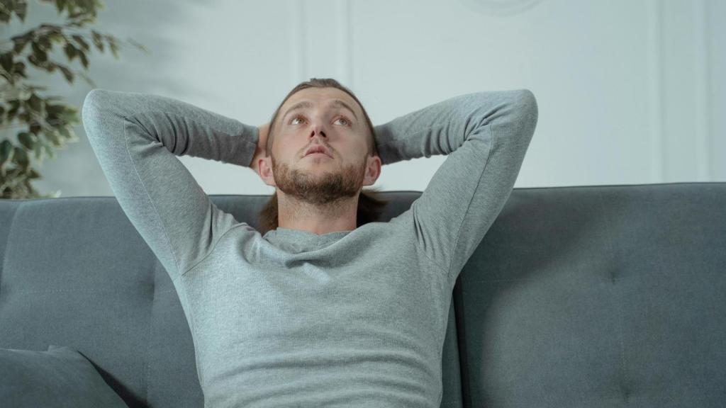 Man sitting on the couch staring up at the ceiling