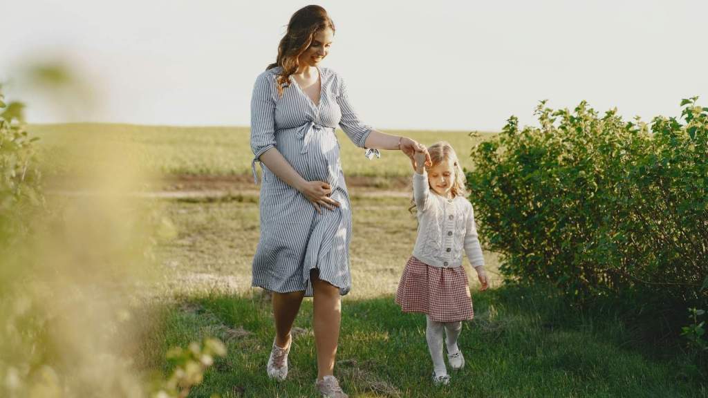 Pregnant mother holding her daughter's hand