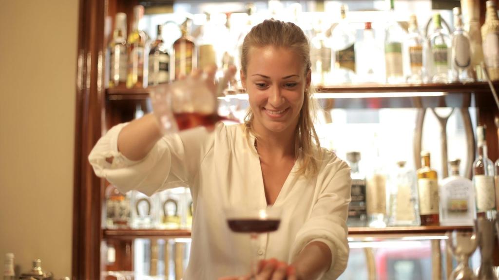 Woman bartender pouring drinks for a customer