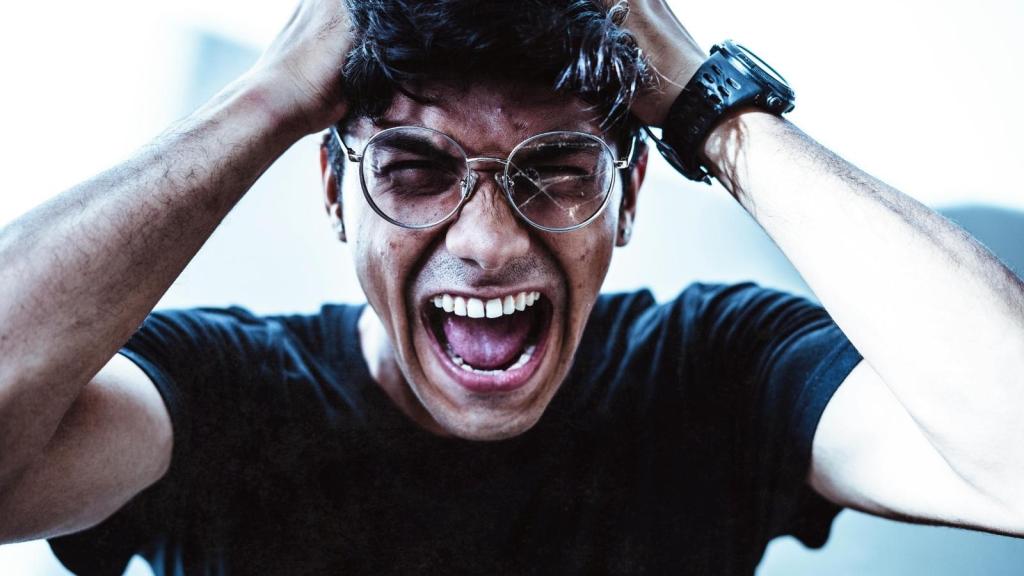 Man holding his hair and yelling as he's having a bad day.