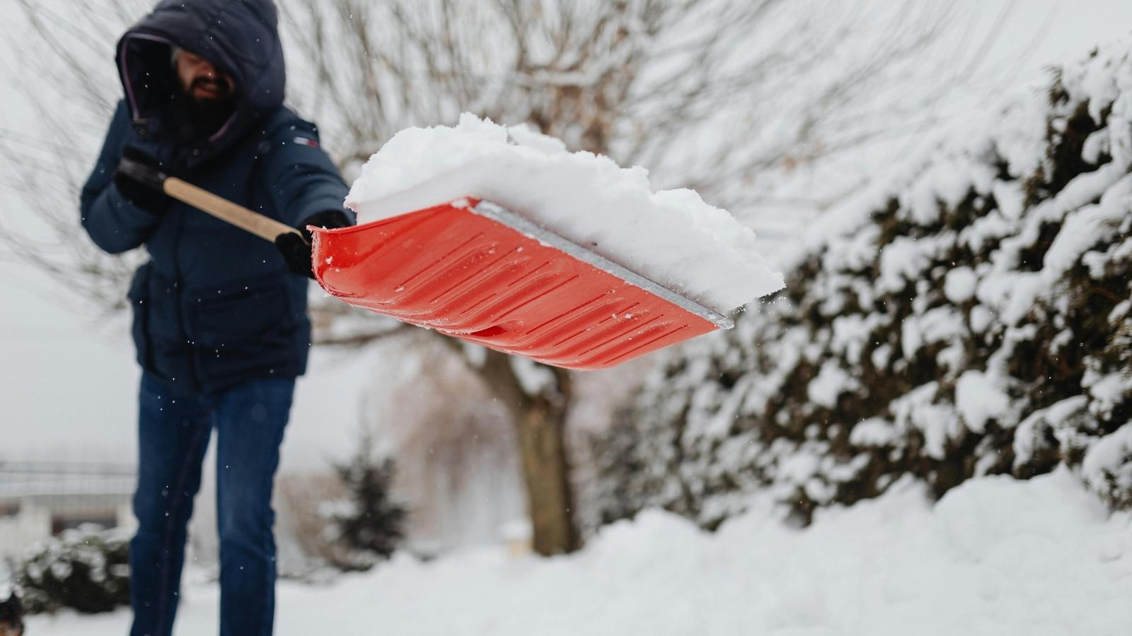 man shoveling with a red shovel