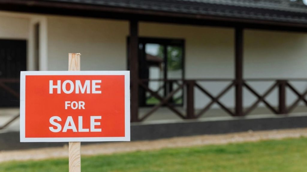 Sign in front of a house that reads "home for sale"