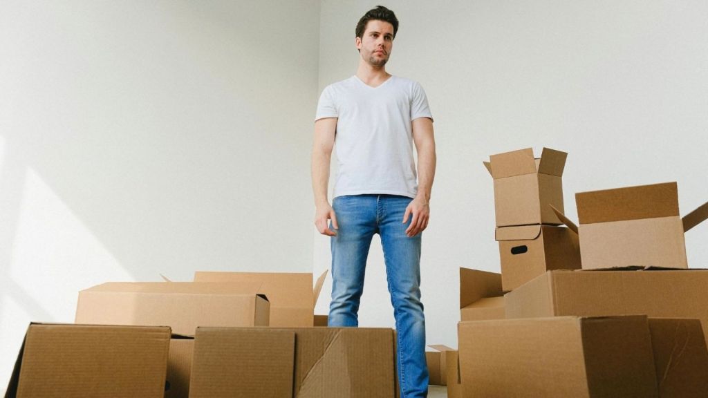 man surrounded by moving boxes