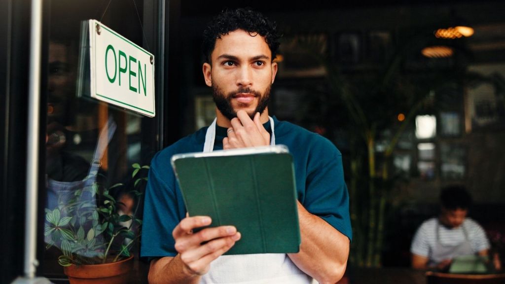 male server standing in restaurant doorway looking worried
