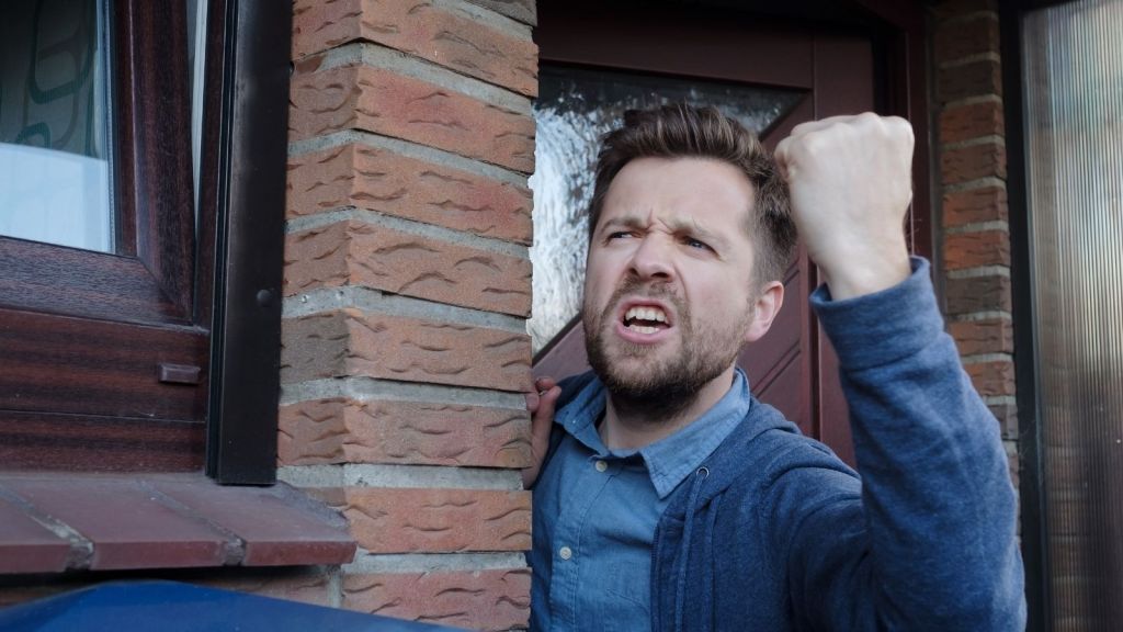 angry man standing in the front door of his house yelling