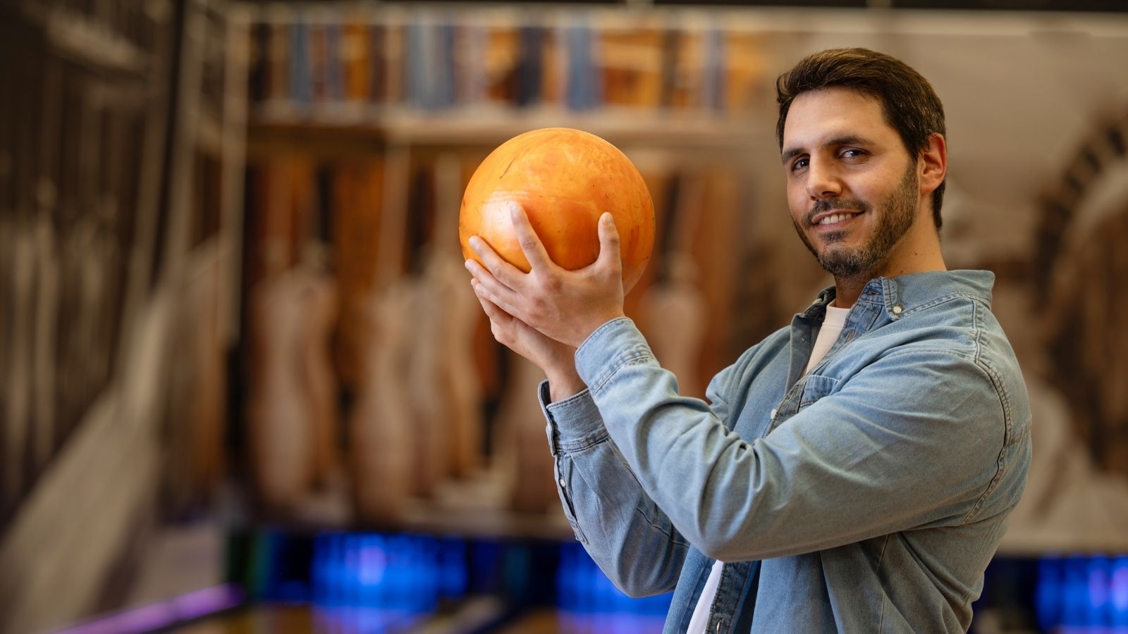 College Student Doesn’t Have the Money for Rent, so He Considers Asking His Rich Friend for a Loan man holding an orange bowling ball