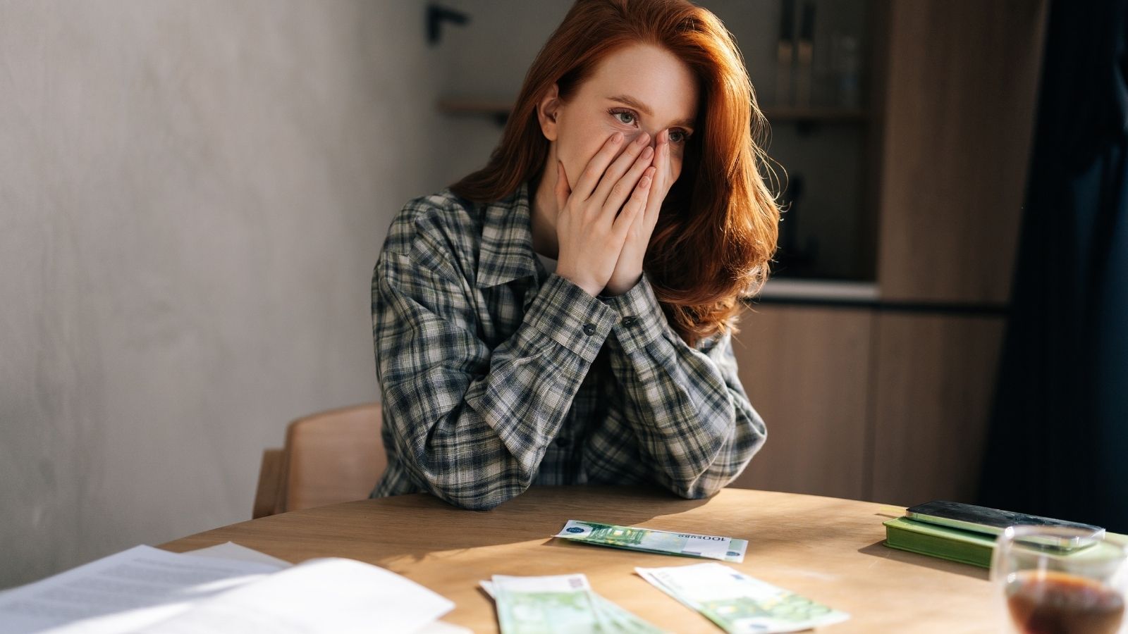 young woman with her hands over her face stressed out about money