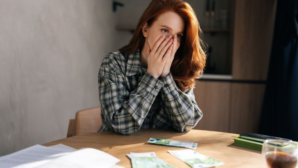 young woman with her hands over her face stressed out about money