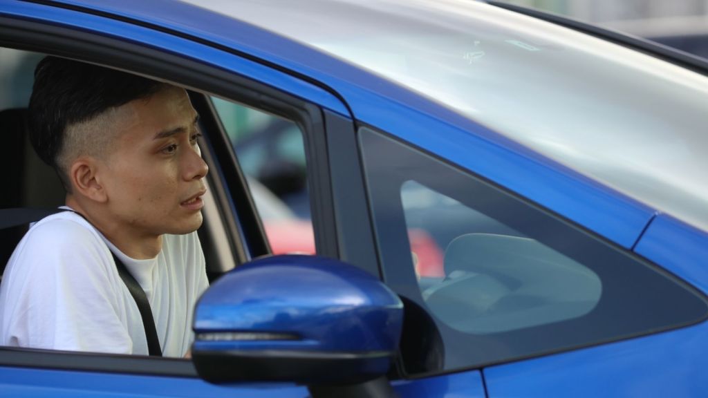 man with anxiety sitting in a blue car