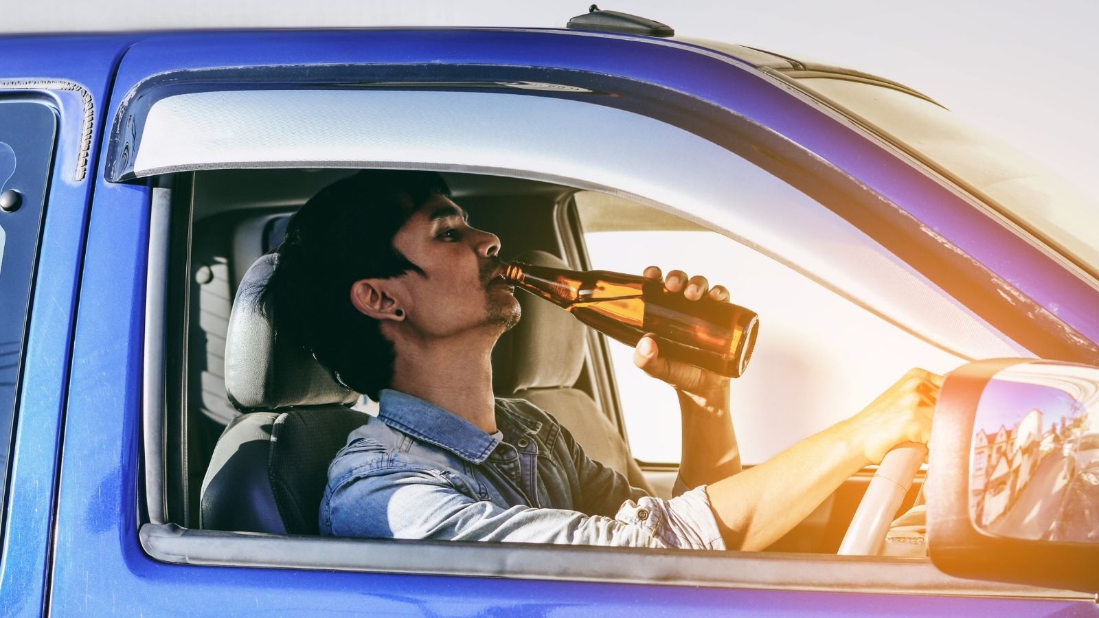 man drinking beer while driving