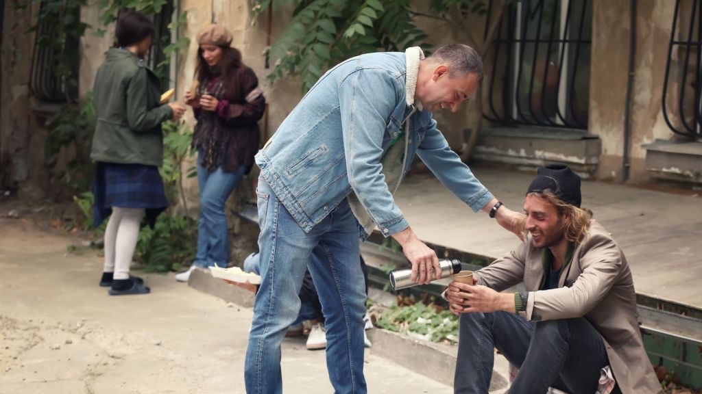 man giving homeless man something to drink