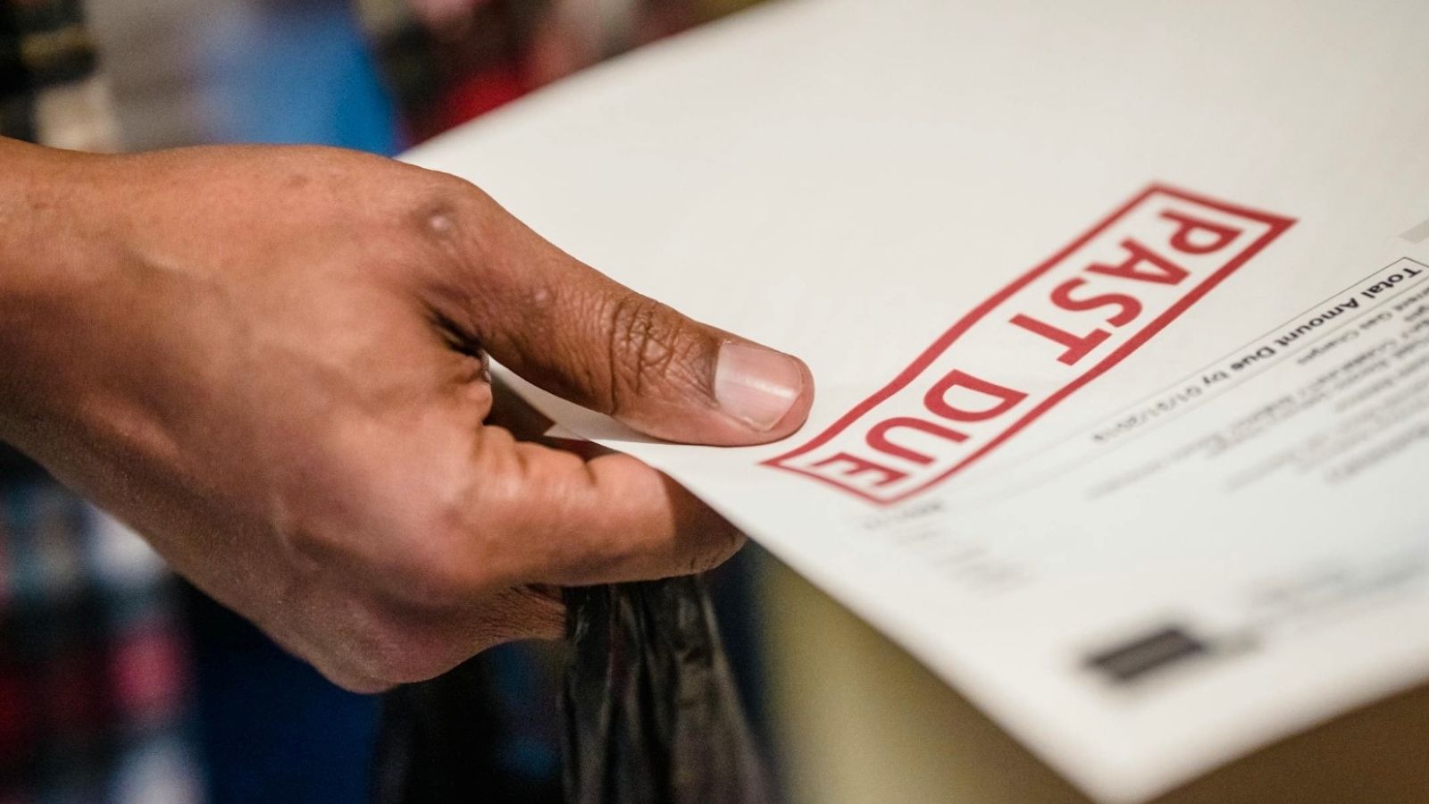 closeup of man's hand holding bill stamped past due