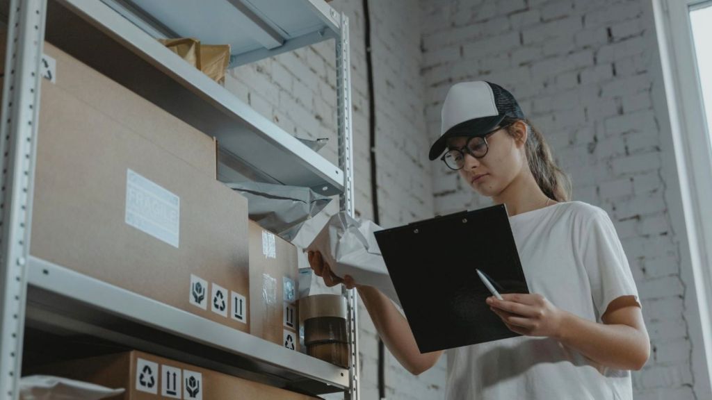 young woman holding a clipboard and organizing boxes