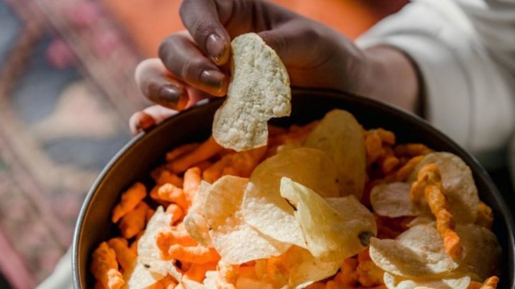closeup of woman picking up a chip out of a bowl of chips
