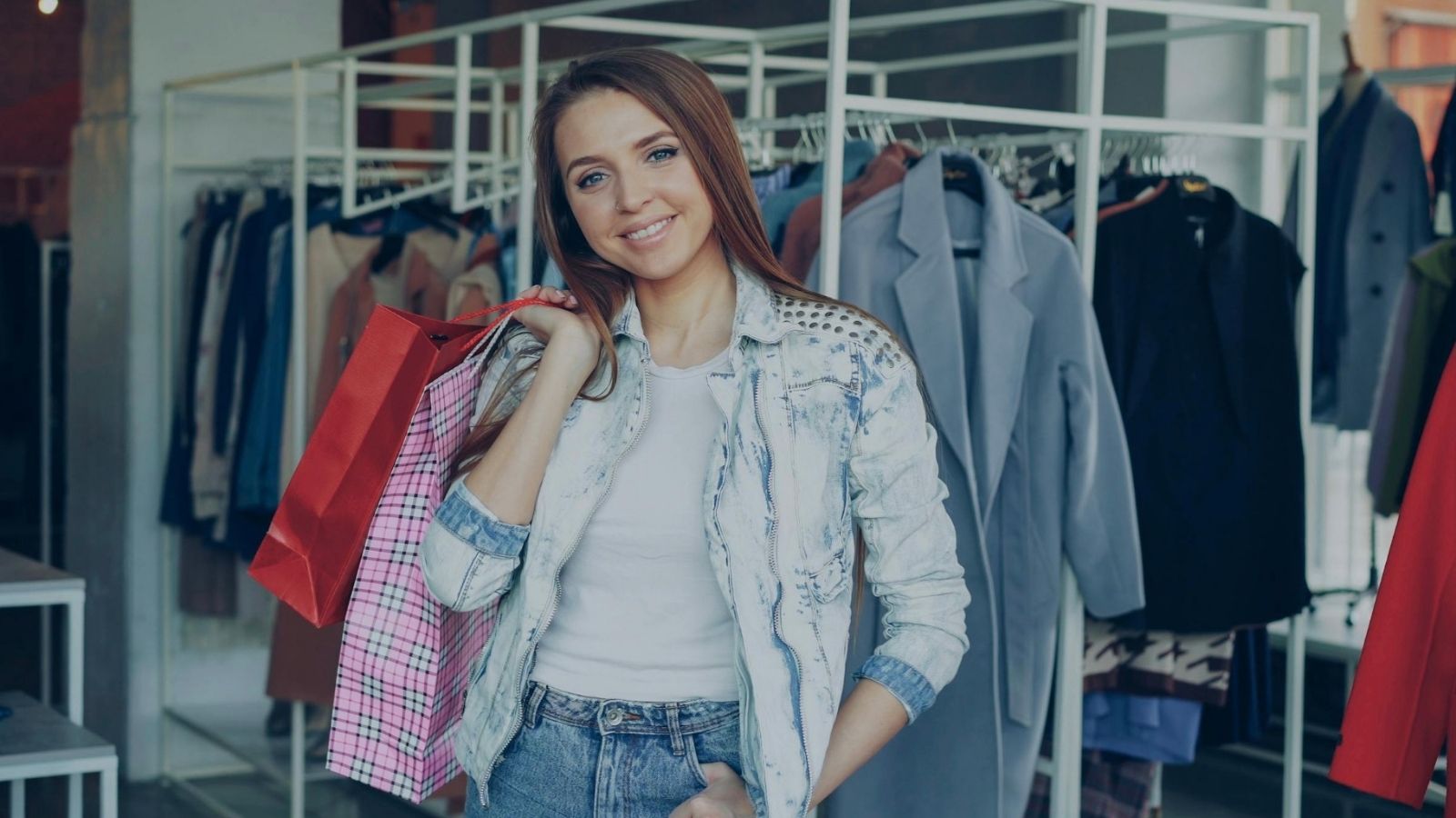 smiling teenage girl holding shopping bags in a clothing store