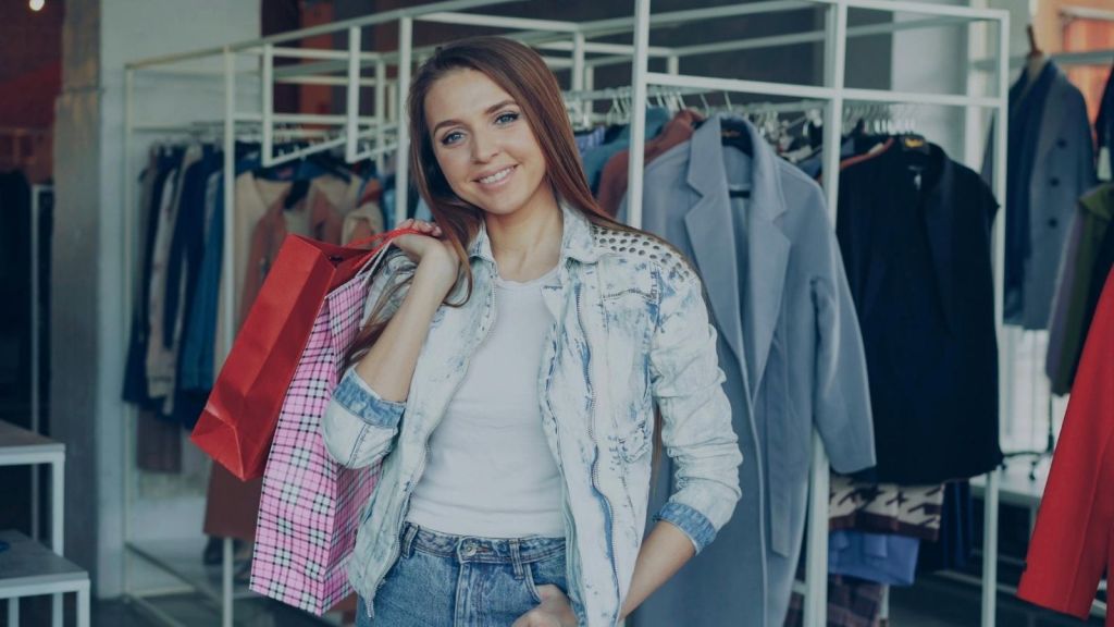 smiling teenage girl holding shopping bags in a clothing store