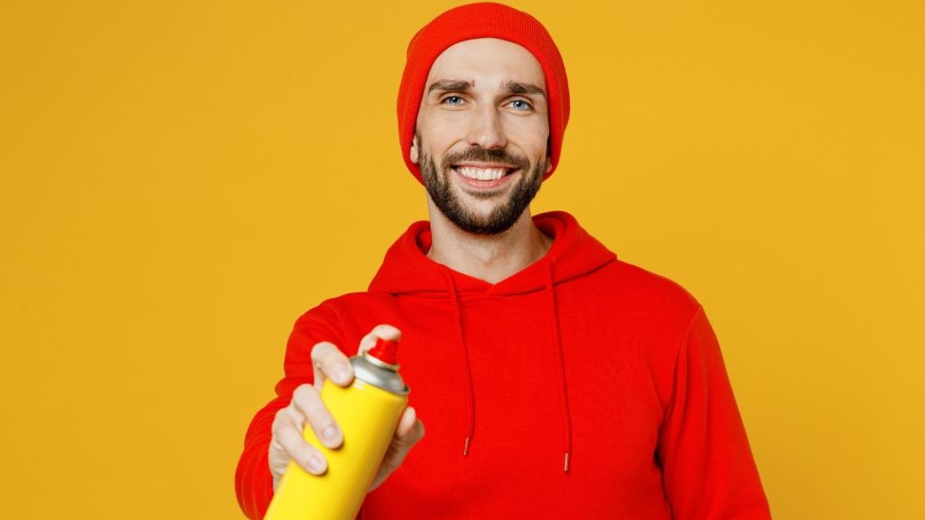 man holding bottle of yellow spray paint