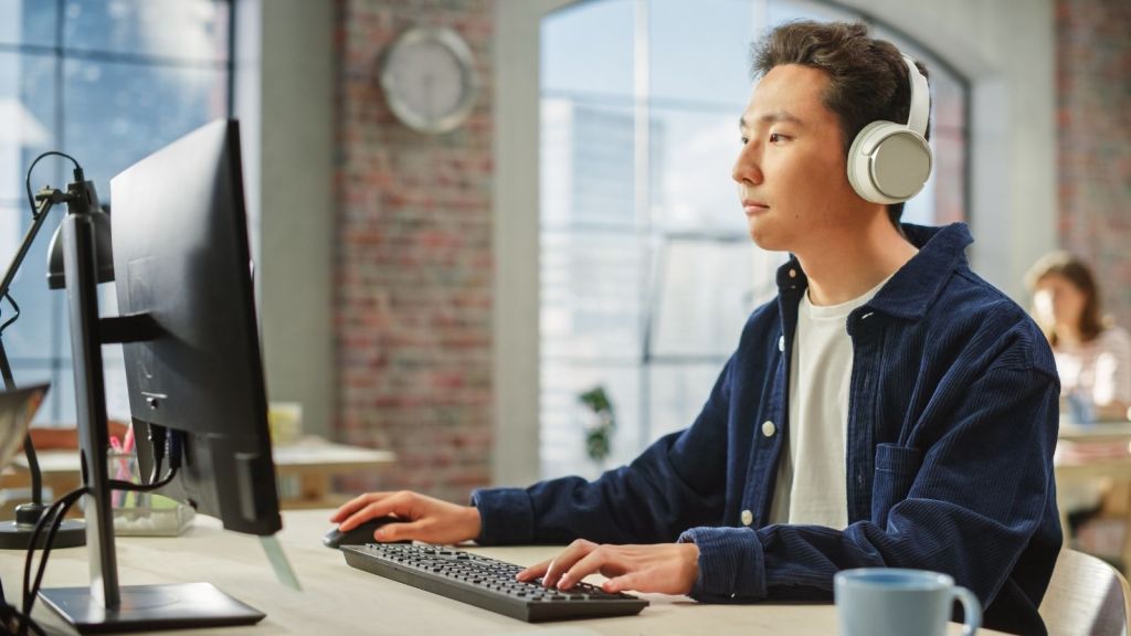man wearing headphones while looking at computer in office
