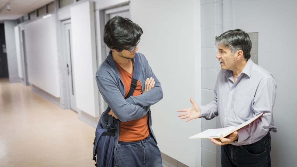 Phd student talking to older professor in hallway