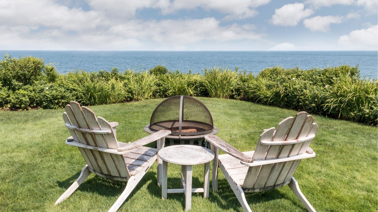 two chairs and a firepit with a sea view