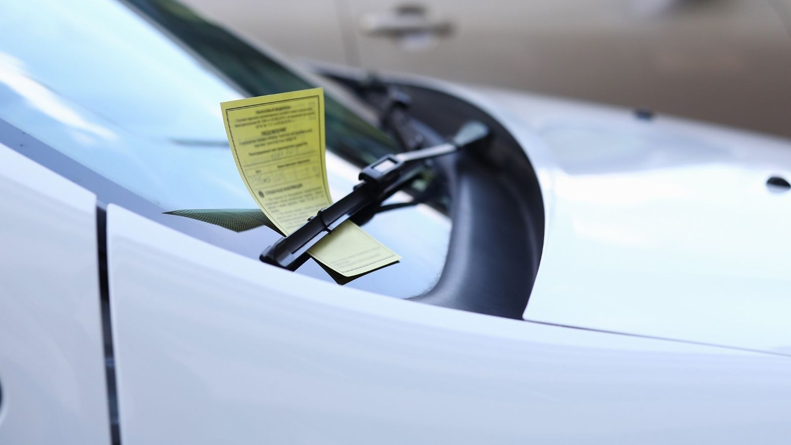Woman Receives Parking Ticket After Using Multiple Paid Lots, Then Disputes Charge With Visa parking ticket left under the windshield of a white car