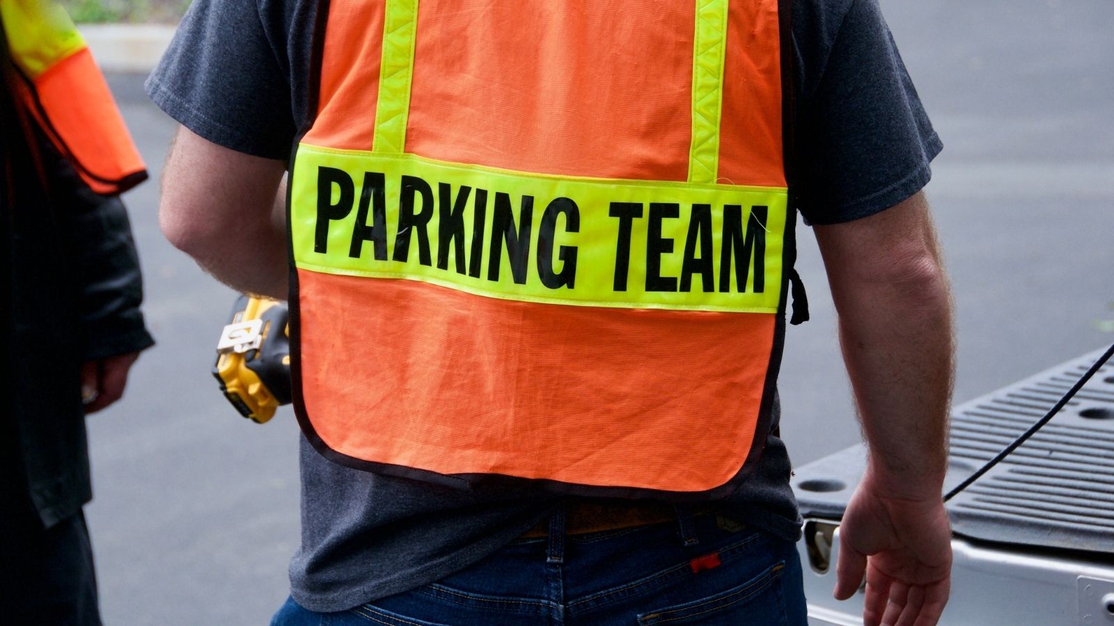 man wearing orange and yellow vest that reads "parking team"