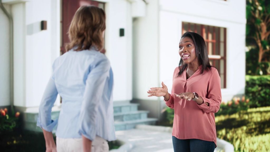 two women talking in front of a house