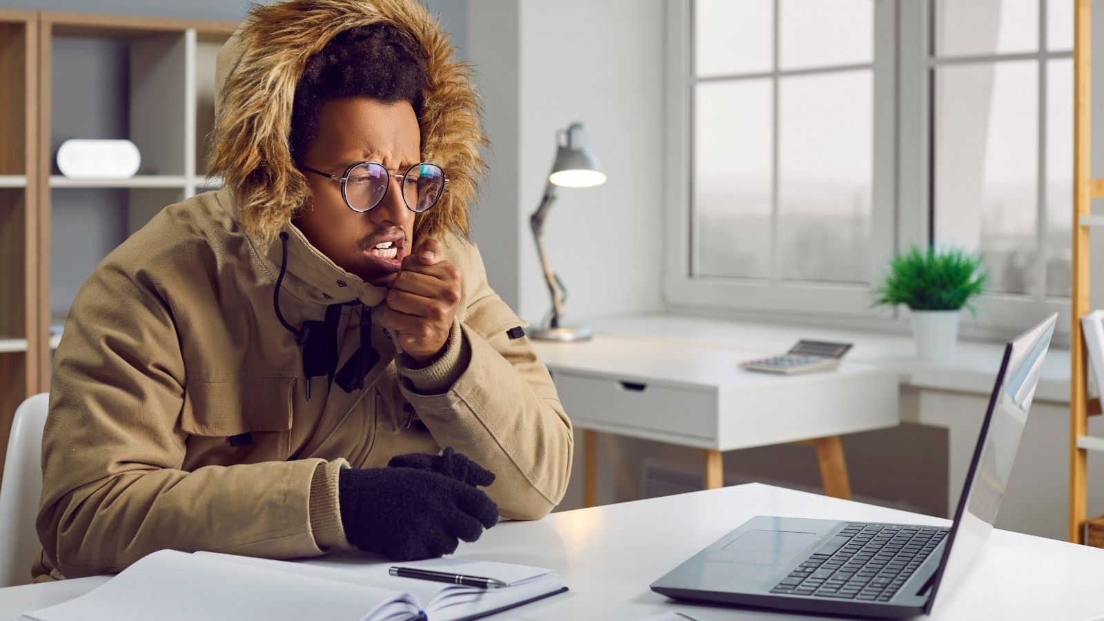 Landlord Doesn’t Allow Space Heaters, so One Tenant Buys a Toaster Oven and Plans to Leave It On All the Time man wearing a warm coat while sitting at a desk