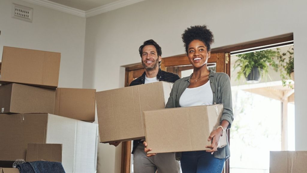 happy couple holding moving boxes