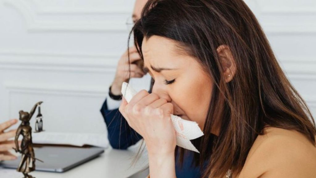 upset businesswoman holding a tissue to her face
