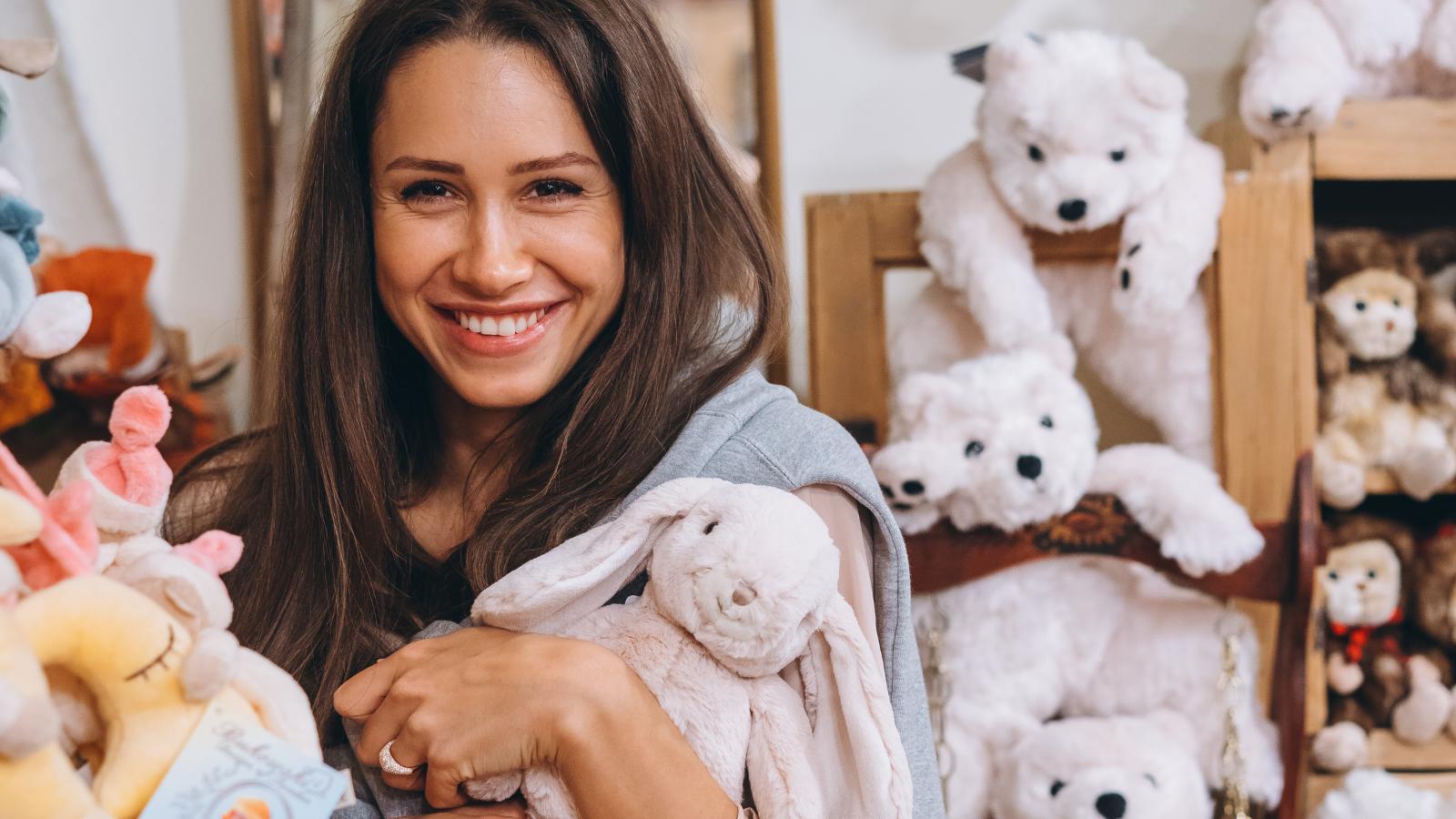 Woman smiling and holding a stuffed toy in a store